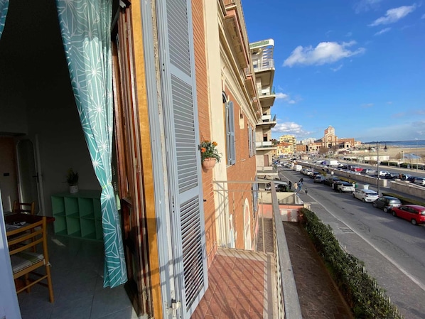 Un balcon donnant sur une rue animée, avec un bâtiment historique en arrière-plan.