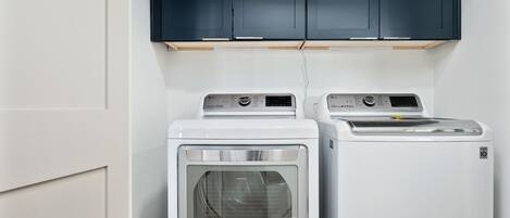 A laundry area with two front-loading washing machines and dark cabinets above.