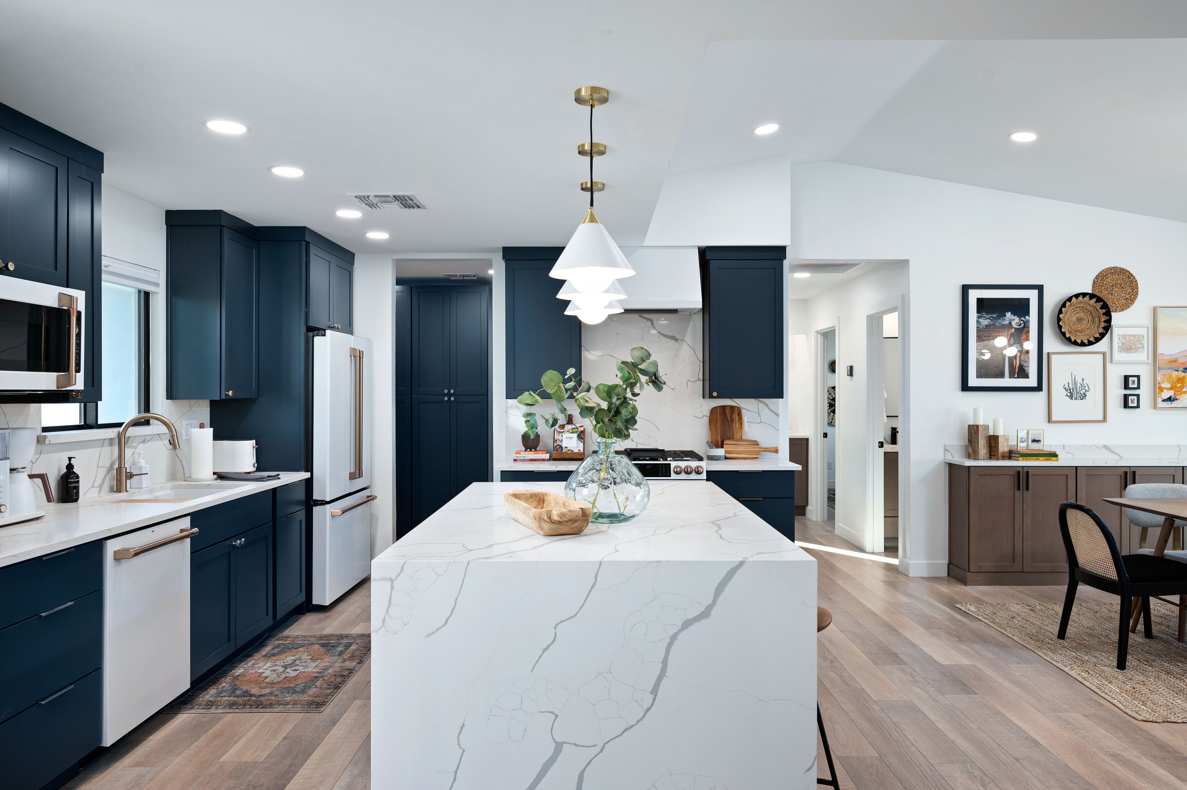 Une cuisine moderne avec des meubles bleu foncé, des plans de travail blancs et un îlot en marbre.
