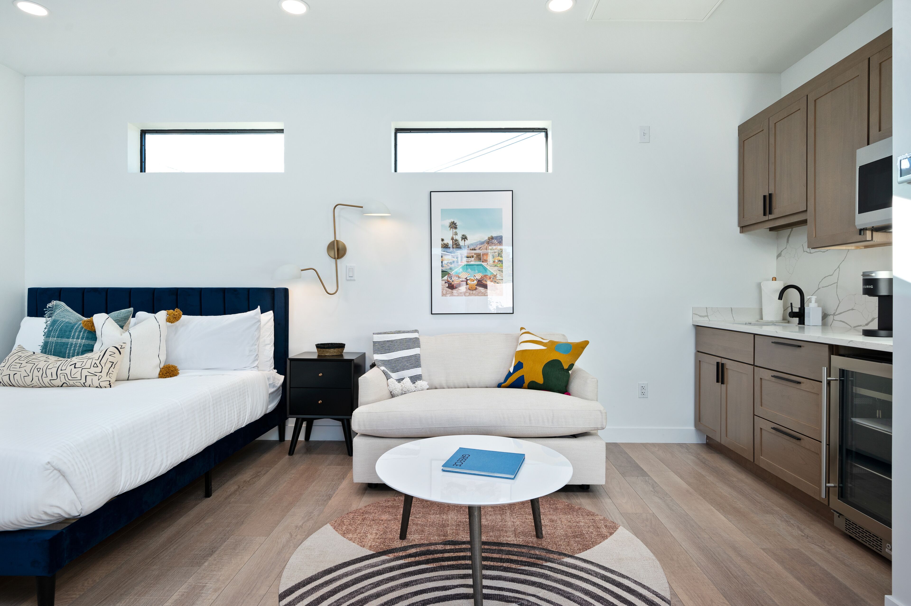 Een moderne slaapkamer met een bed, een slaapbank, een salontafel en een keuken met kasten en apparatuur.