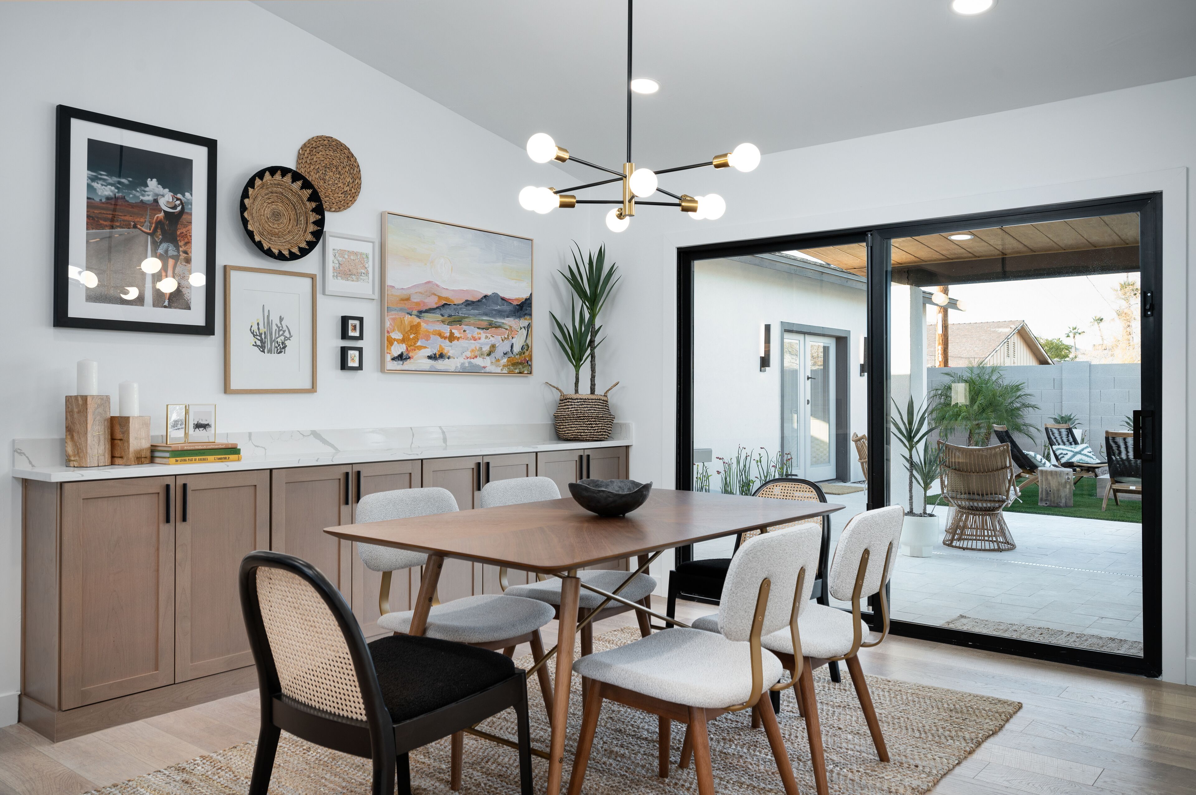 A modern kitchen with a dining area, featuring a large table, chairs, and a hanging light fixture.