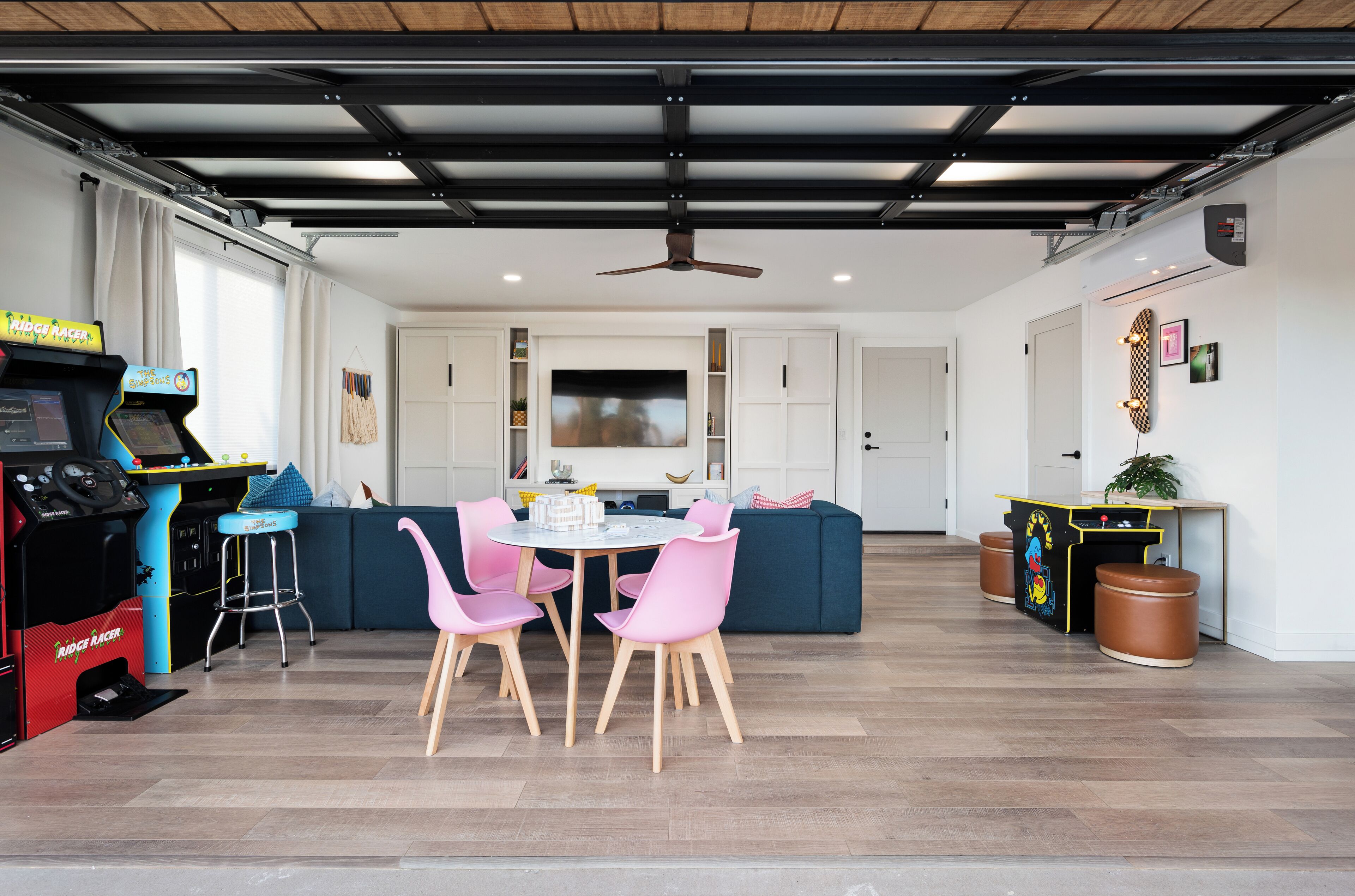 A modern kitchen with a dining area, a ceiling fan, and a children's arcade game.