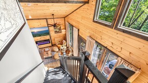 A wooden interior with a staircase leading to a lower level, a dining area with a view, and a large window. - Near Dollywood | Hot Tub, Fire Pit & Games (Sevierville)