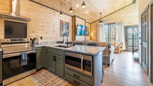 A modern kitchen with stainless steel appliances, a large island, and wooden ceiling. - Near Dollywood | Hot Tub, Fire Pit & Games (Sevierville)