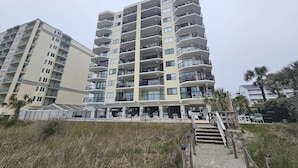 A multi-story hotel with balconies, a pool area, and a beach access walkway. - Beautiful Oceanfront Top-Floor Condo, Pool, Beach View, (North Myrtle Beach)