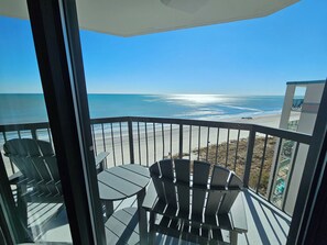 A balcony with a view of the ocean, featuring a table and chairs. - Beautiful Oceanfront Top-Floor Condo, Pool, Beach View, (North Myrtle Beach)