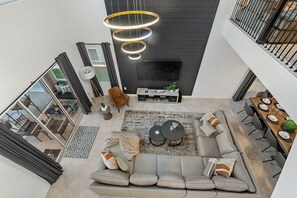 Una sala moderna con un sofá seccional, una mesa de centro y un televisor. Se ve una escalera que sube a un nivel superior.