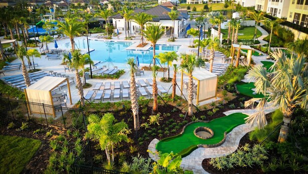 Un resort con una piscina grande, tumbonas, palmeras y un jardín bien cuidado.