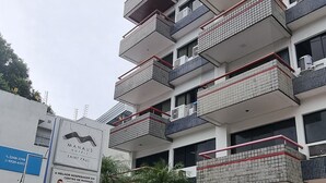 A multi-story hotel with a modern design, featuring balconies and a landscaped entrance area.