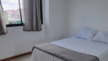 Un dormitorio con una cama, una ventana con cortinas y un suelo de baldosas.