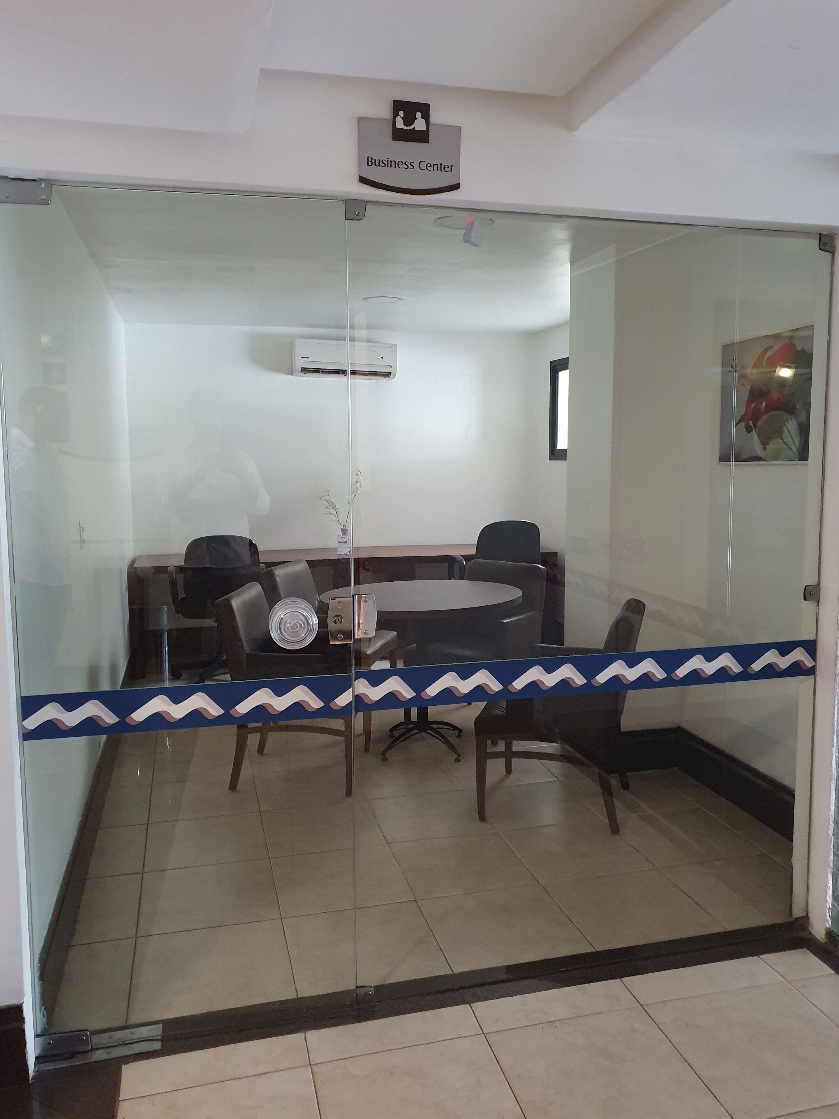 Un centro de negocios con mampara de vidrio, una mesa redonda y varias sillas.