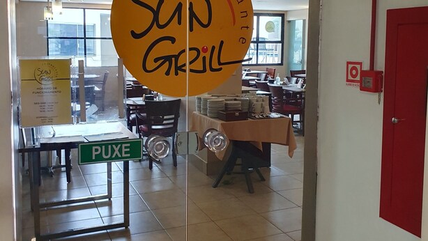 A restaurant entrance with a glass door, a 'PUXE' sign, and a 'SUN GRILL' sign.
