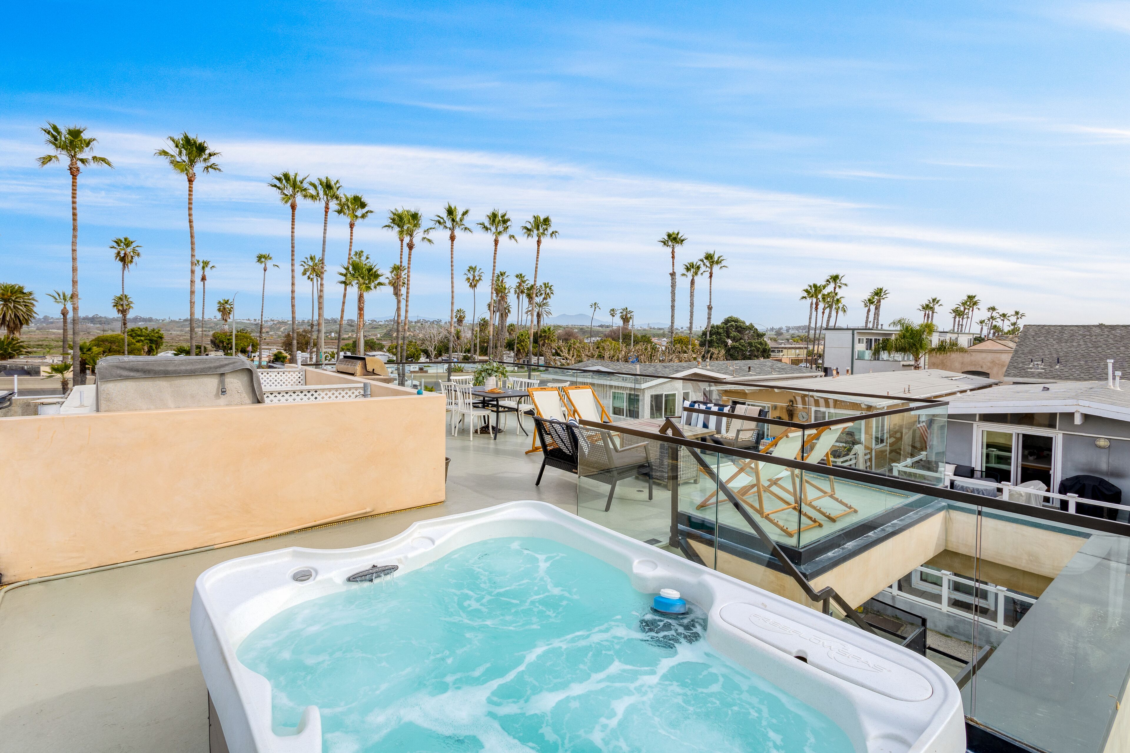 Un área de piscina en la azotea con un jacuzzi, sillones de descanso y palmeras al fondo.