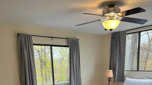 A bedroom with a bed, a ceiling fan, and a view of the outdoors through large windows. - Lazy O Resort - 7 bedroom 3 bathroom house. (Camdenton)