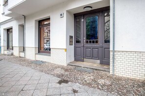 Stylish entrance to a residential unit with a large door and glass panel, flanked by windows.