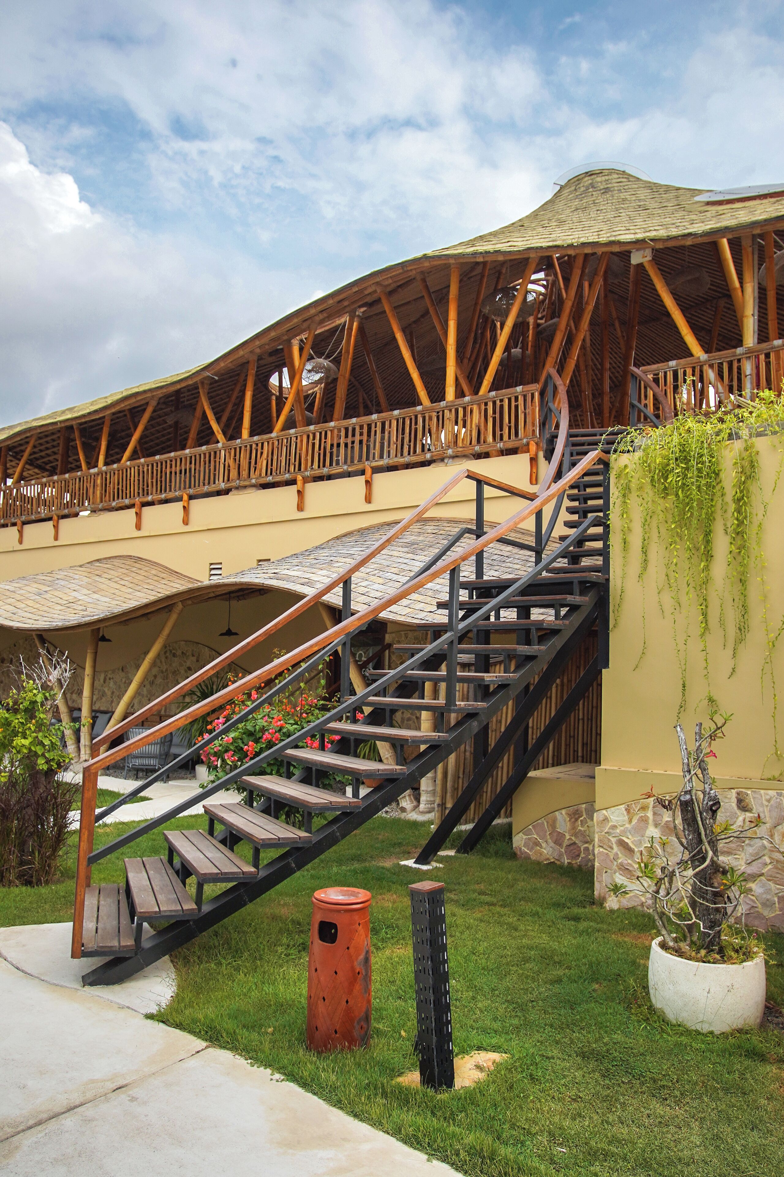 A building with a wooden staircase leading to a covered area with benches and a view of the sky.