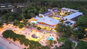 Vista aerea di un resort con diversi edifici, una zona piscina e una spiaggia.