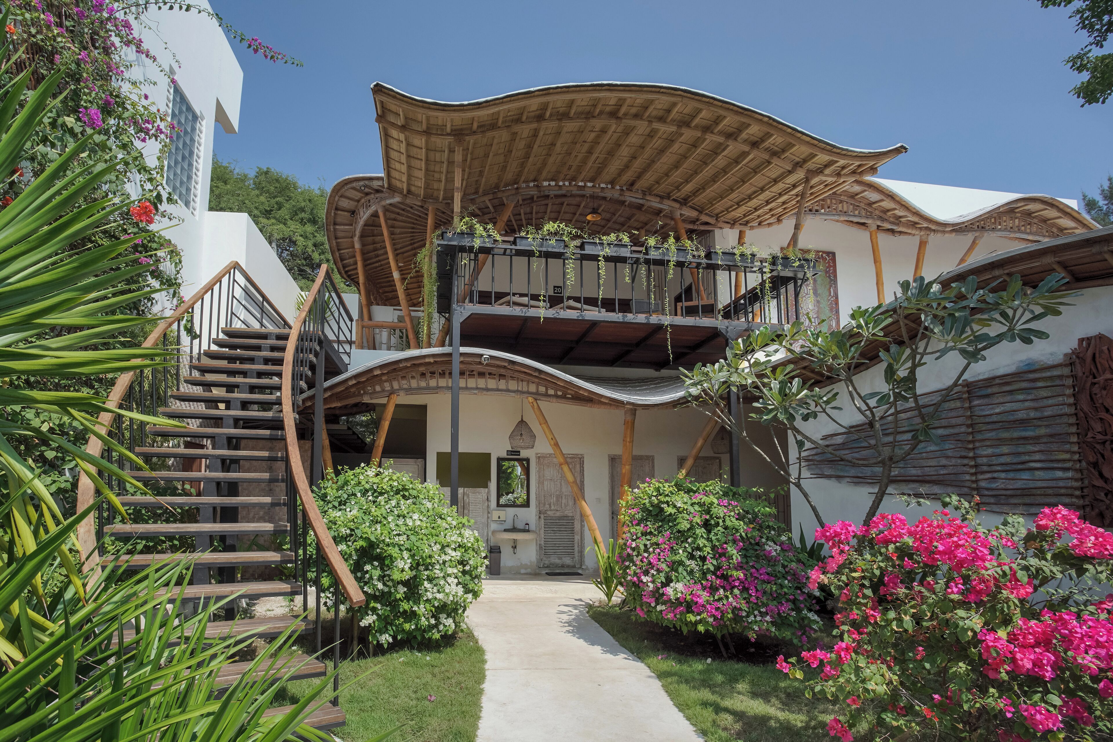 A modern building with a curved roof, a staircase, and a pathway leading to the entrance.