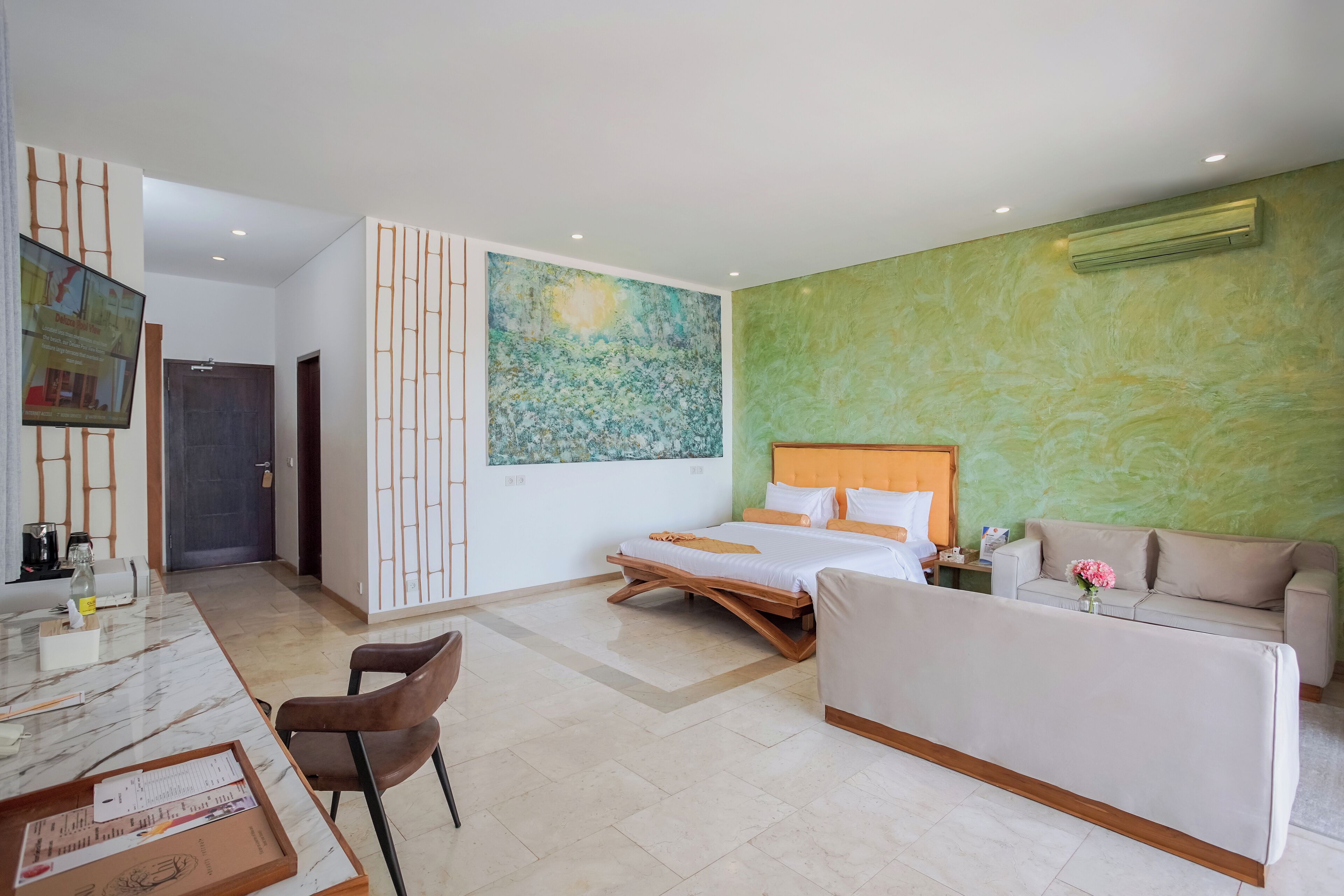 A modern hotel room with a bed, a sofa, a TV, and a dining area.