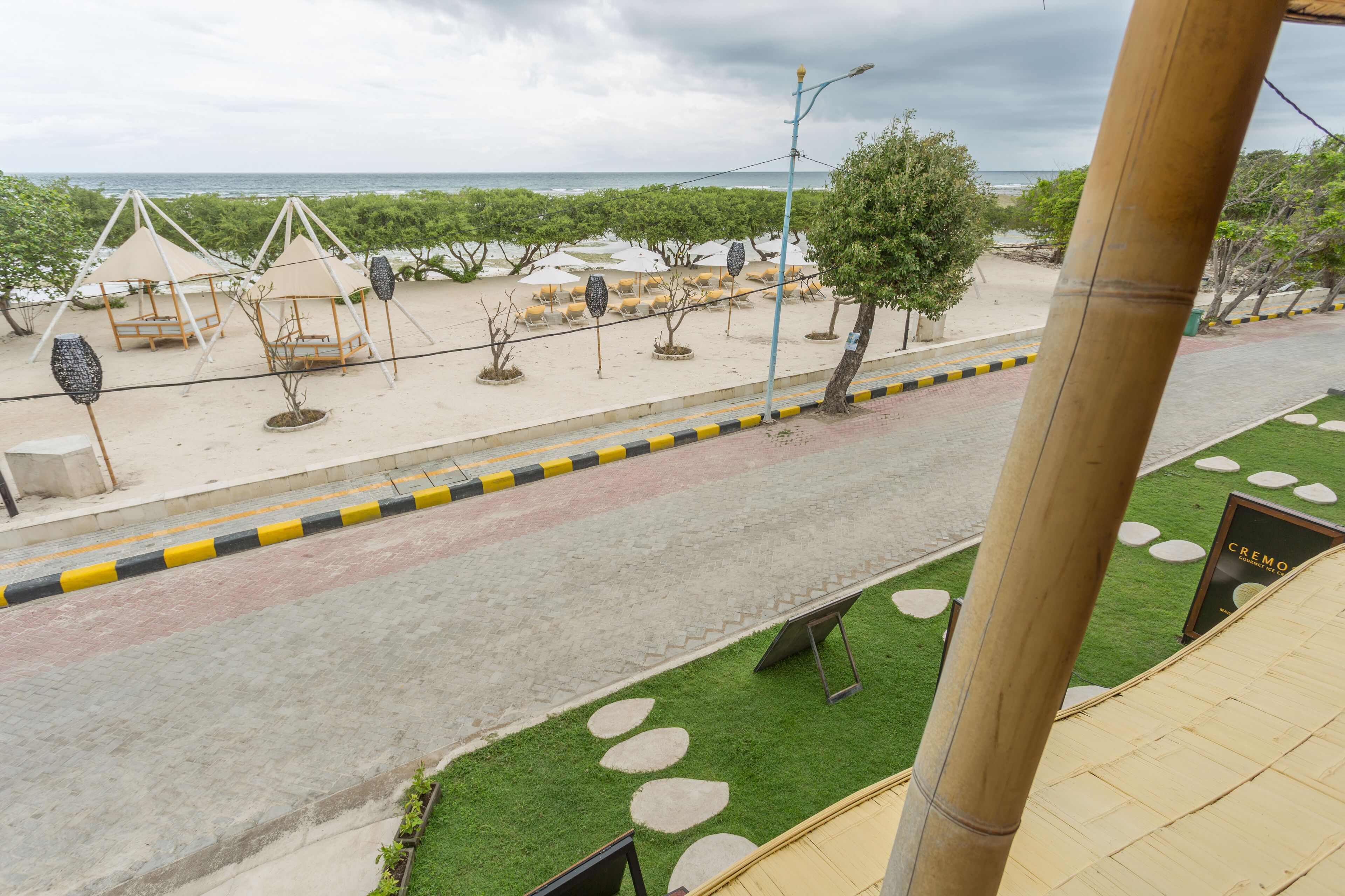 Vista de la playa con un sendero pavimentado, sombrillas y algunas tiendas de campaña.