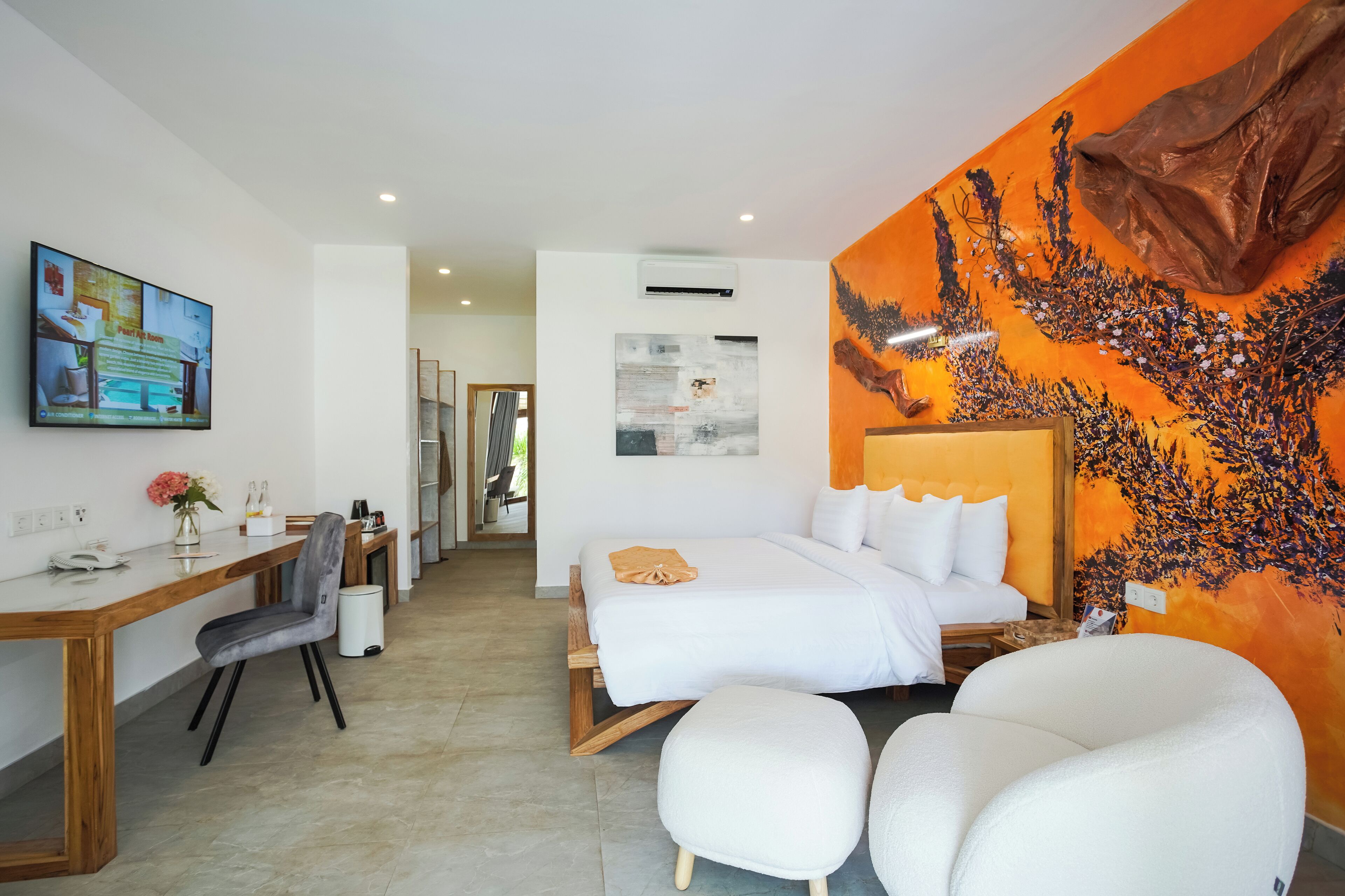 A modern hotel room with a bed, a desk, a chair, and a large painting on the wall.