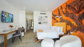 A modern hotel room with a bed, a desk, a chair, and a large painting on the wall.