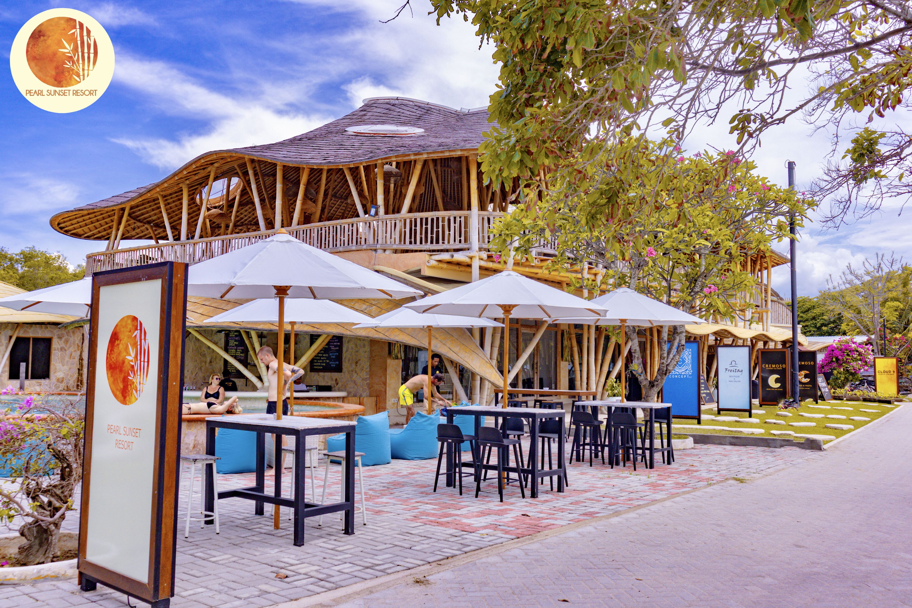 A resort with outdoor seating, a wooden structure, and a sign for 'Pearl Sunset Resort'.
