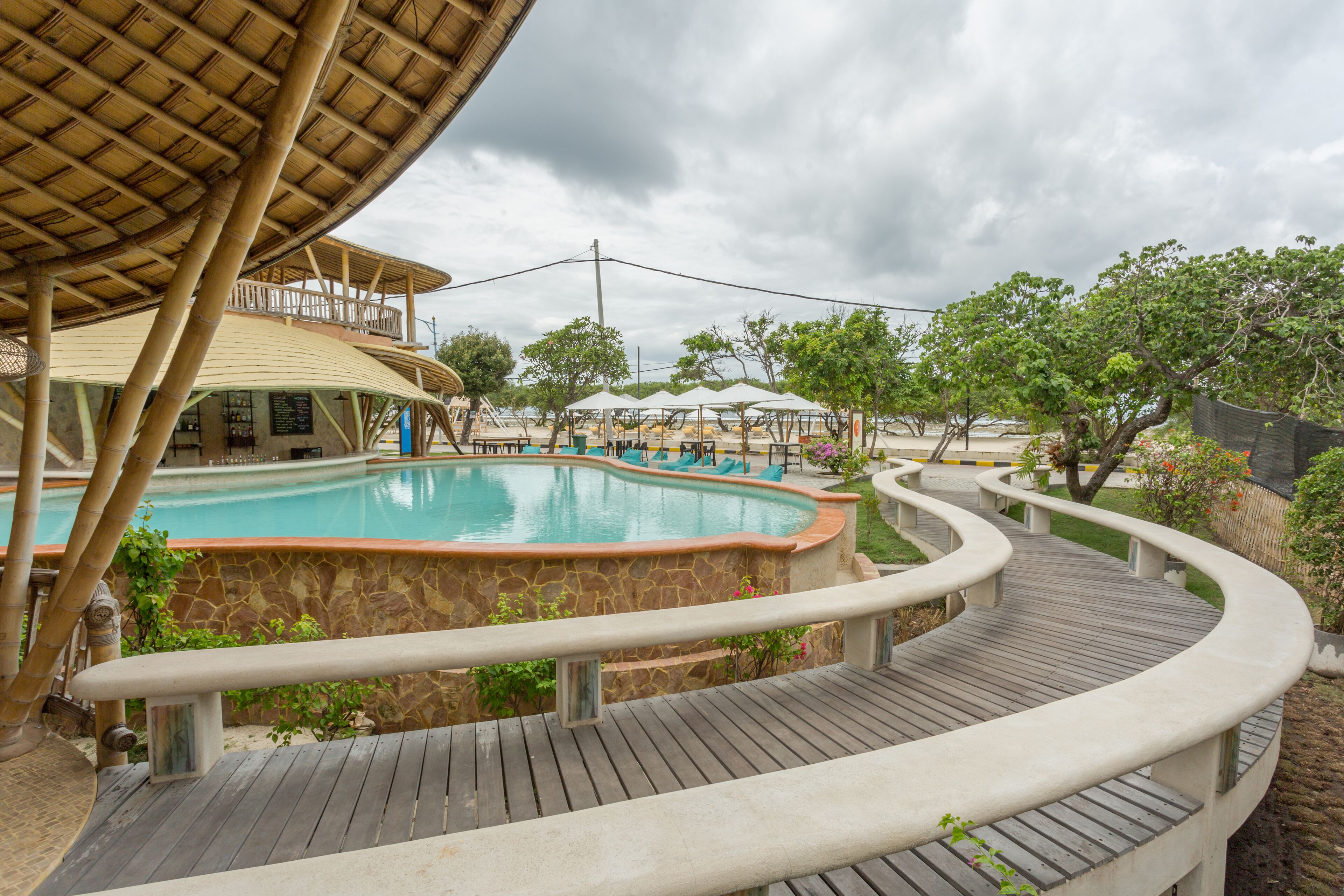 A pool area with a wooden deck, stone walls, and a covered seating area.
