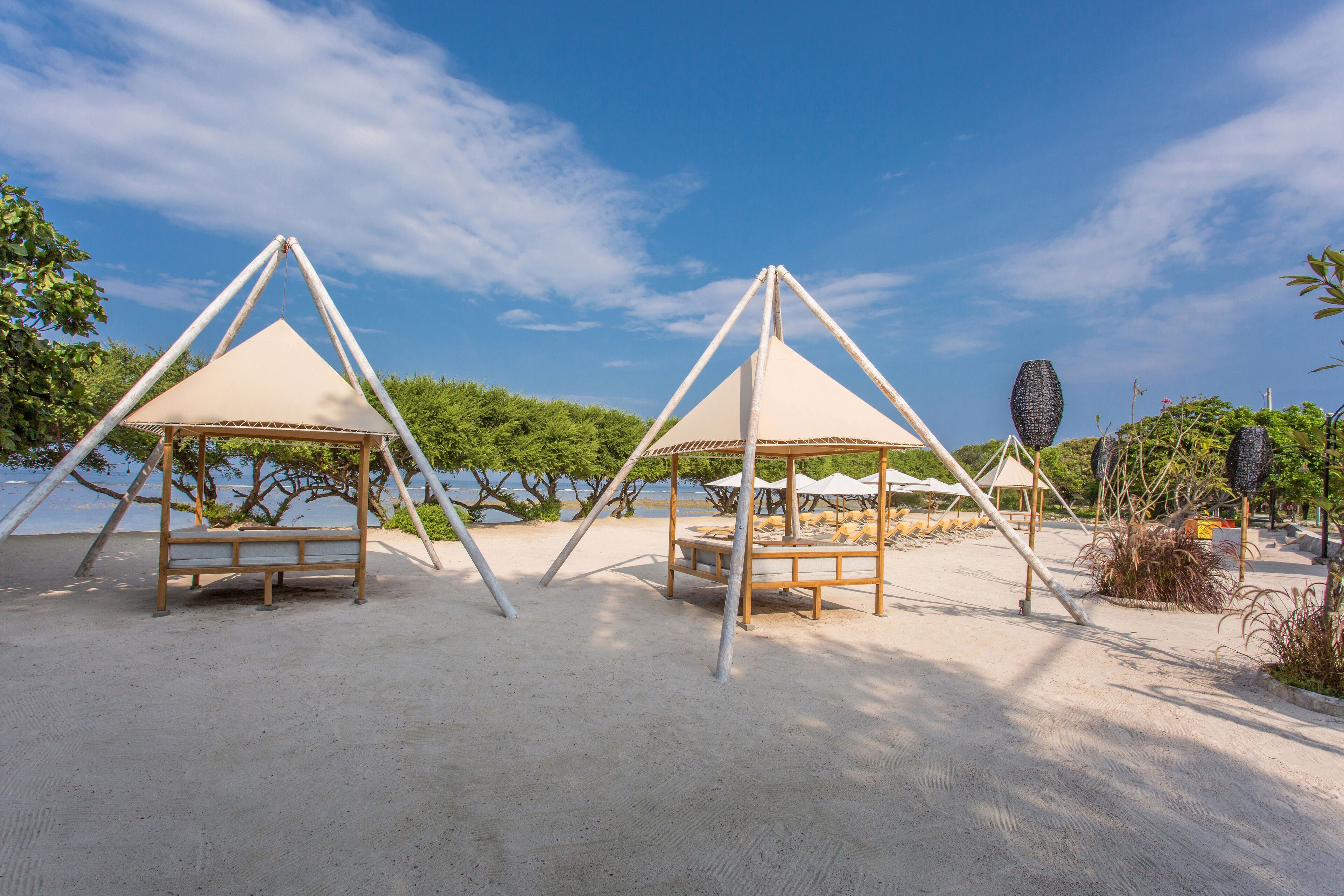 A beach with two wooden gazebos and a sandy area.