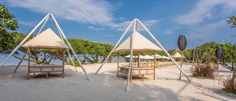 A beach with two wooden gazebos and a sandy area.