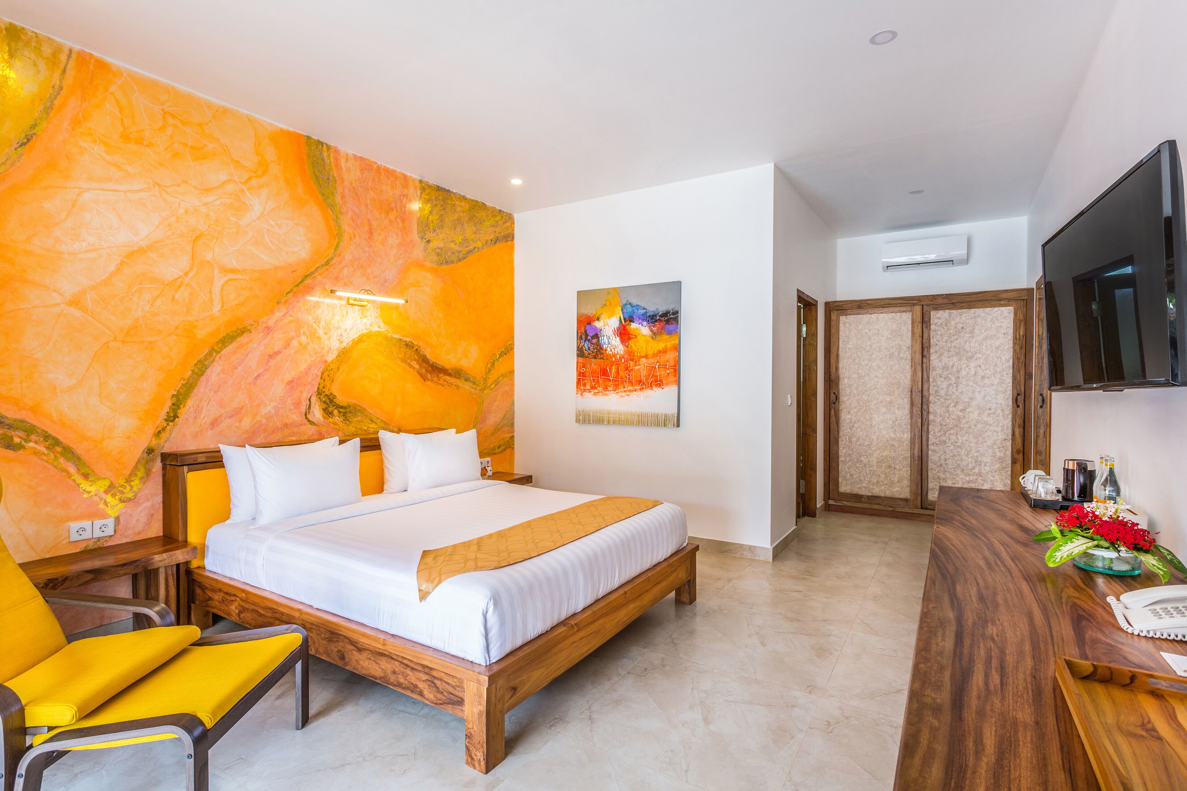 Una habitación de hotel moderna con una cama de madera, una silla amarilla, un escritorio con teléfono y una televisión en la pared.
