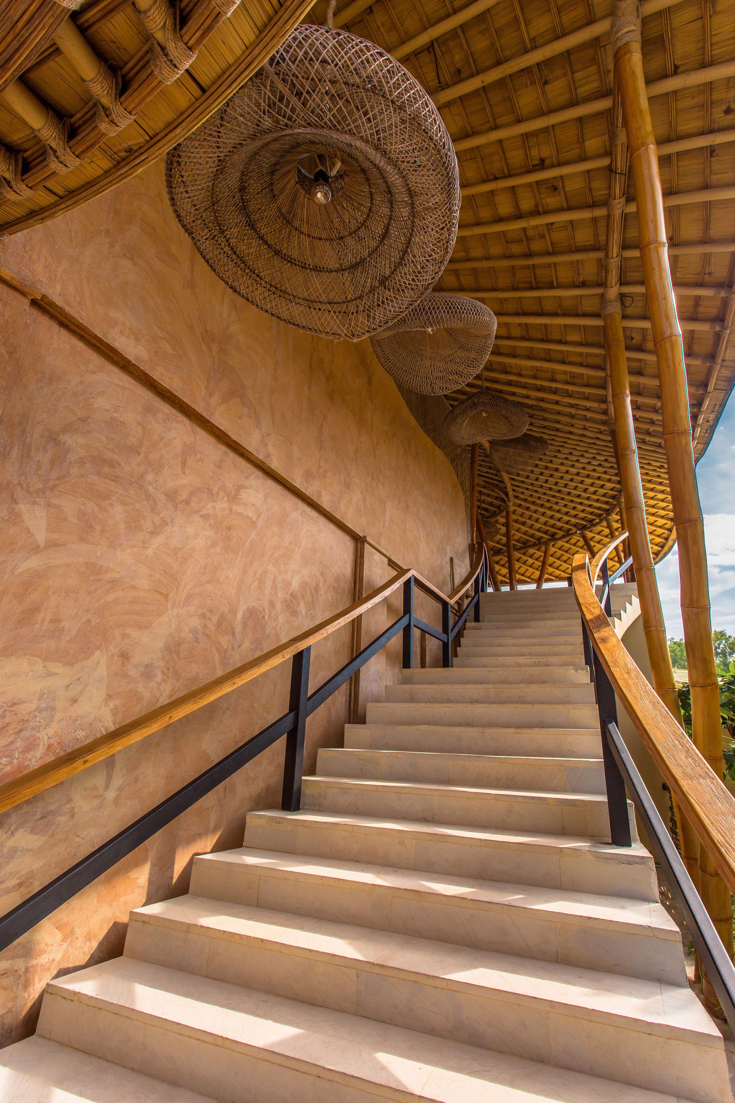 A staircase with a bamboo ceiling and woven light fixtures.