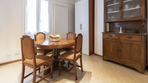 Ein Esszimmer mit einem runden Holztisch, sechs Stühlen, einem Schrank mit Glastüren und einer Heizung.