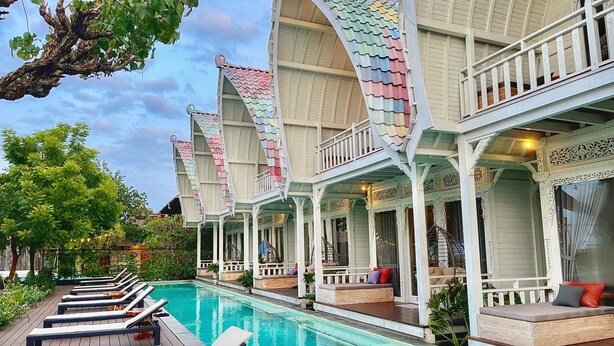 Un área junto a la piscina con sillones de descanso y una pileta.