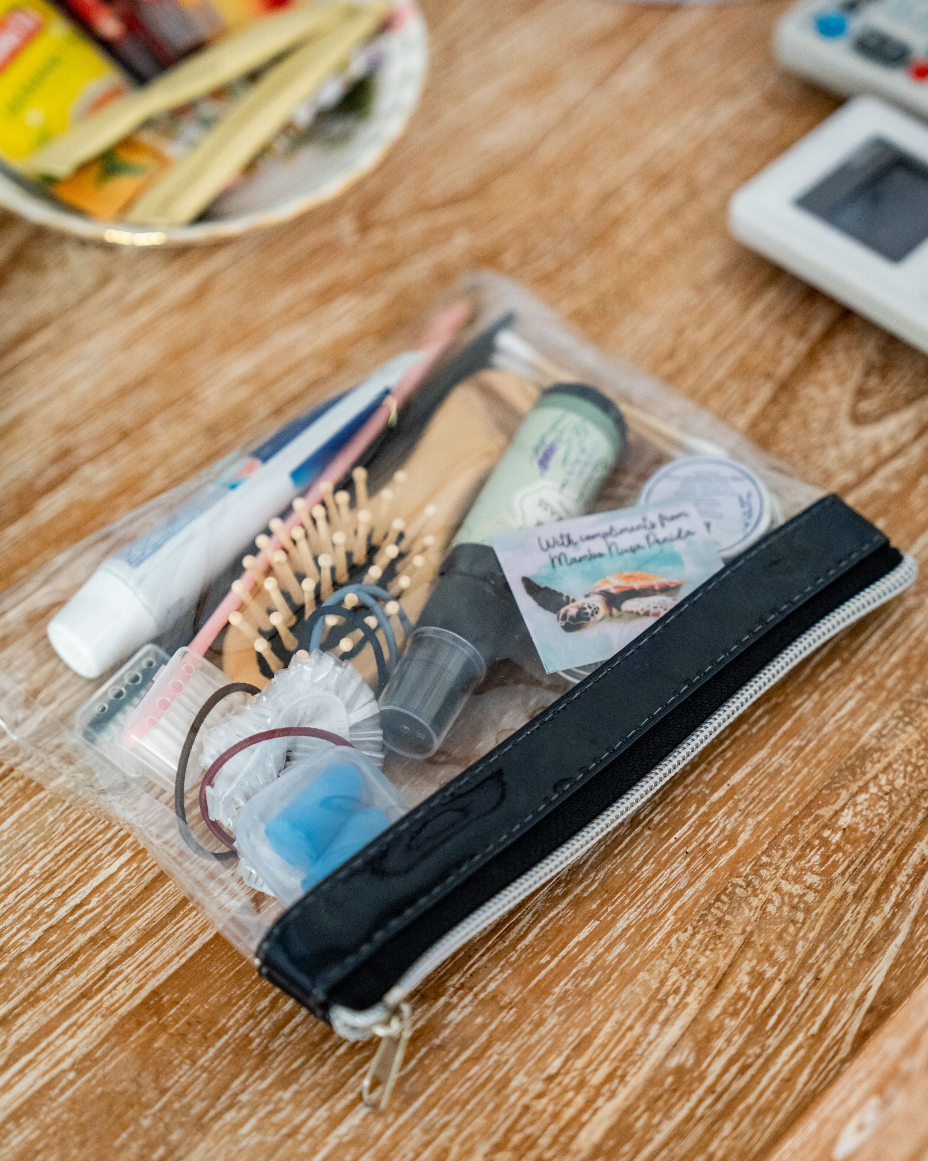 A clear plastic bag containing various personal care items, including a toothbrush, toothpaste, and a comb, placed on a wooden surface.