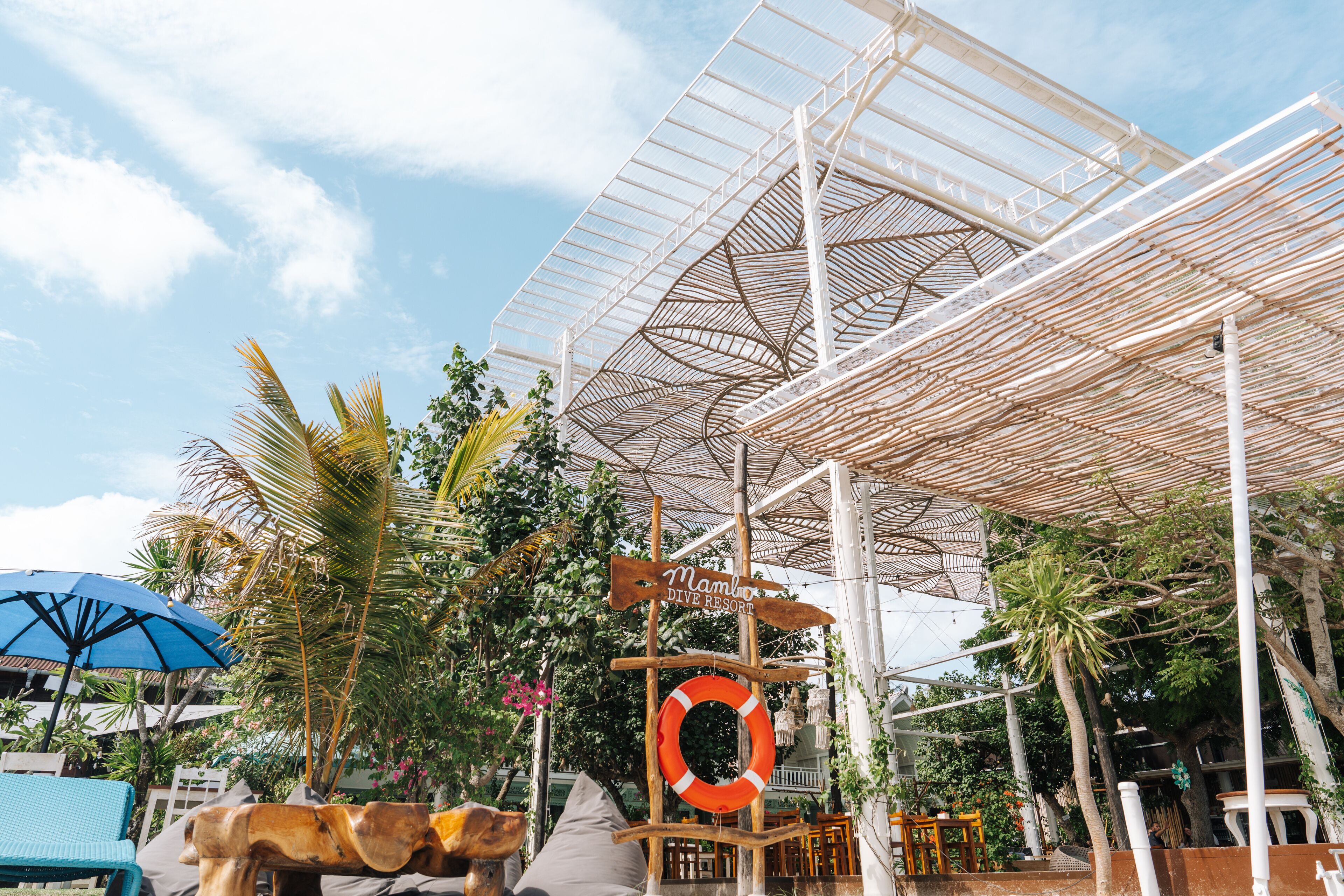 A covered outdoor area with a sign for 'Mambo Dive Resort'.