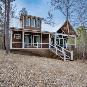 Een chalet met een houten gevel, een schuin dak en een overdekte veranda met een trap.
