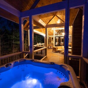 Ein Whirlpoolbereich mit Holzterrasse und Blick in die Hütte.