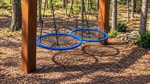 Une balançoire en bois installée dans un espace boisé.