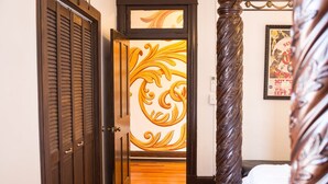 Un couloir avec des portes en bois, un panneau décoratif au mur et un lit avec une tête de lit.