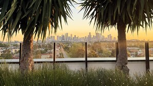 Vista de un horizonte urbano al atardecer, con dos palmeras en primer plano.