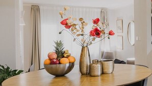 Ein Esstisch mit einer Obstschale, einer Vase mit Trockenblumen und zwei Kerzenständern.