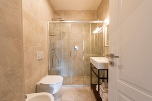 Un baño con ducha de vidrio, inodoro y lavabo con toallero.