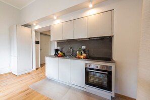 Une cuisine moderne avec des armoires blanches, une hotte de cuisinière en acier inoxydable et un four.