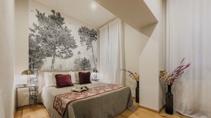 Ein Schlafzimmer mit einem Bett, einem Nachttisch, einer Lampe, einer Wand mit Baum-Fresko und zwei Vasen mit Zweigen.