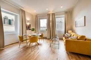 Una sala moderna con un sofá amarillo, una mesa de centro de vidrio y un comedor con sillas amarillas.