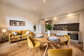 A modern living room with a sofa, coffee table, and dining table set for four.