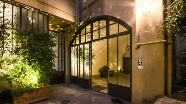 Una entrada exterior con puerta de vidrio, una planta en maceta y un área empedrada con piedra.