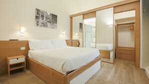 Un dormitorio con cama de madera, mesitas de noche, armario y espejo.