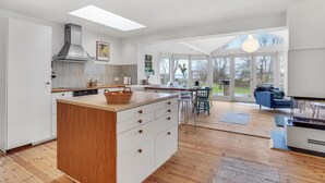A modern kitchen with a central island, large windows, and a dining area with outdoor seating.